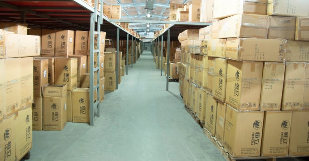 A warehouse aisle with cartons stacked on racking either side.